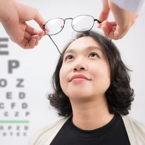 Optometrist giving asian woman eyeglasses to try