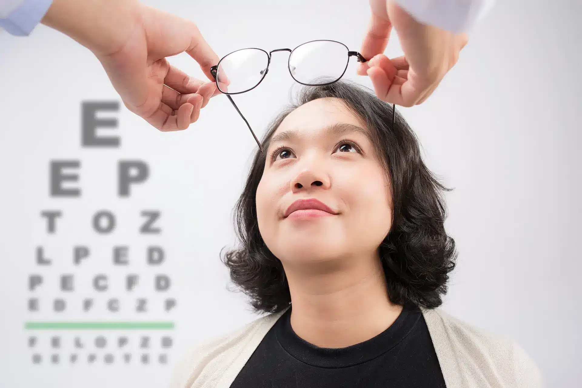 AdobeStock_175796642 Optometrist giving asian woman eyeglasses to try