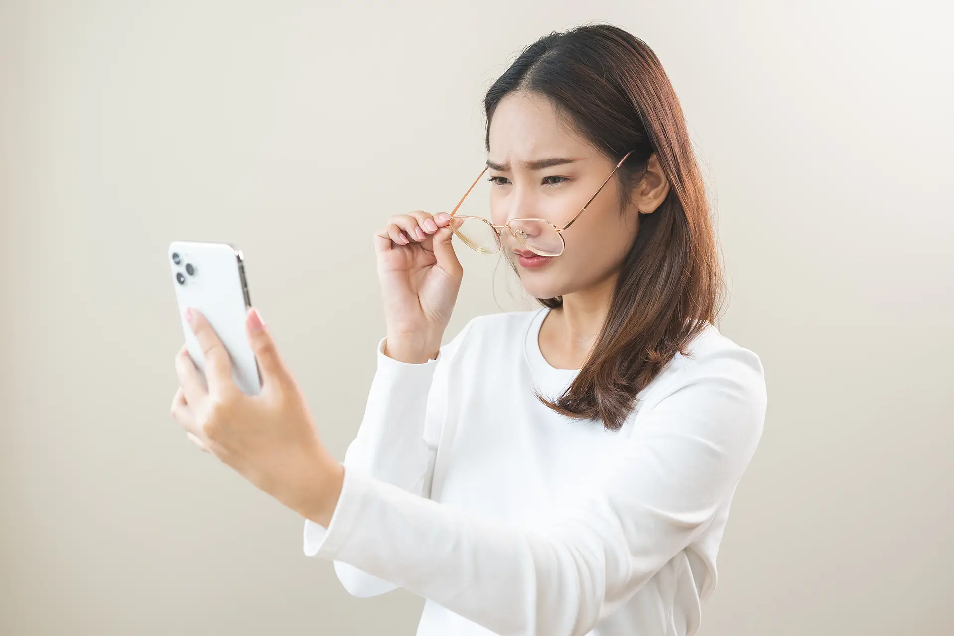 AdobeStock_894843904 Woman looking at her phone squinting